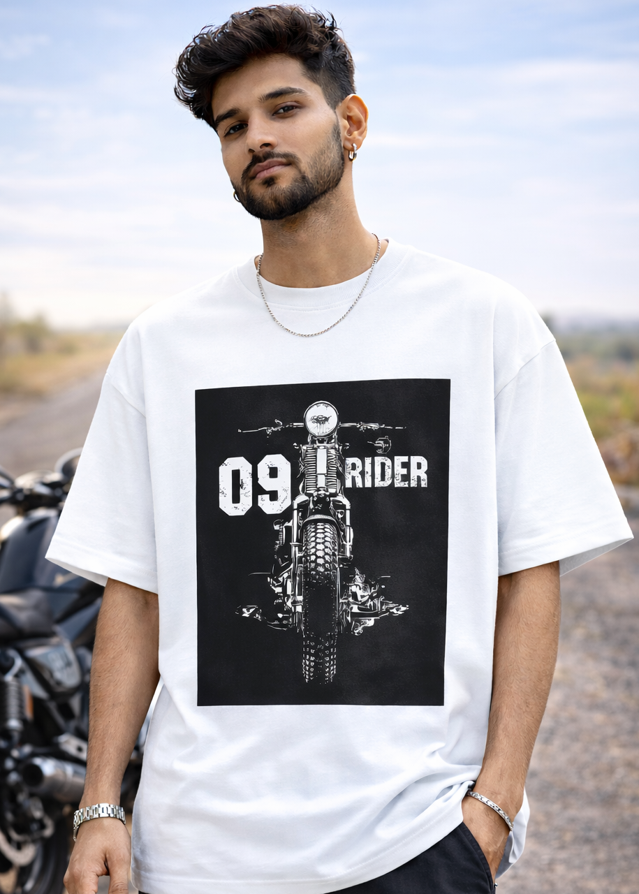 Man wearing a white t-shirt with a graphic design of a motorcycle and text, standing outdoors.