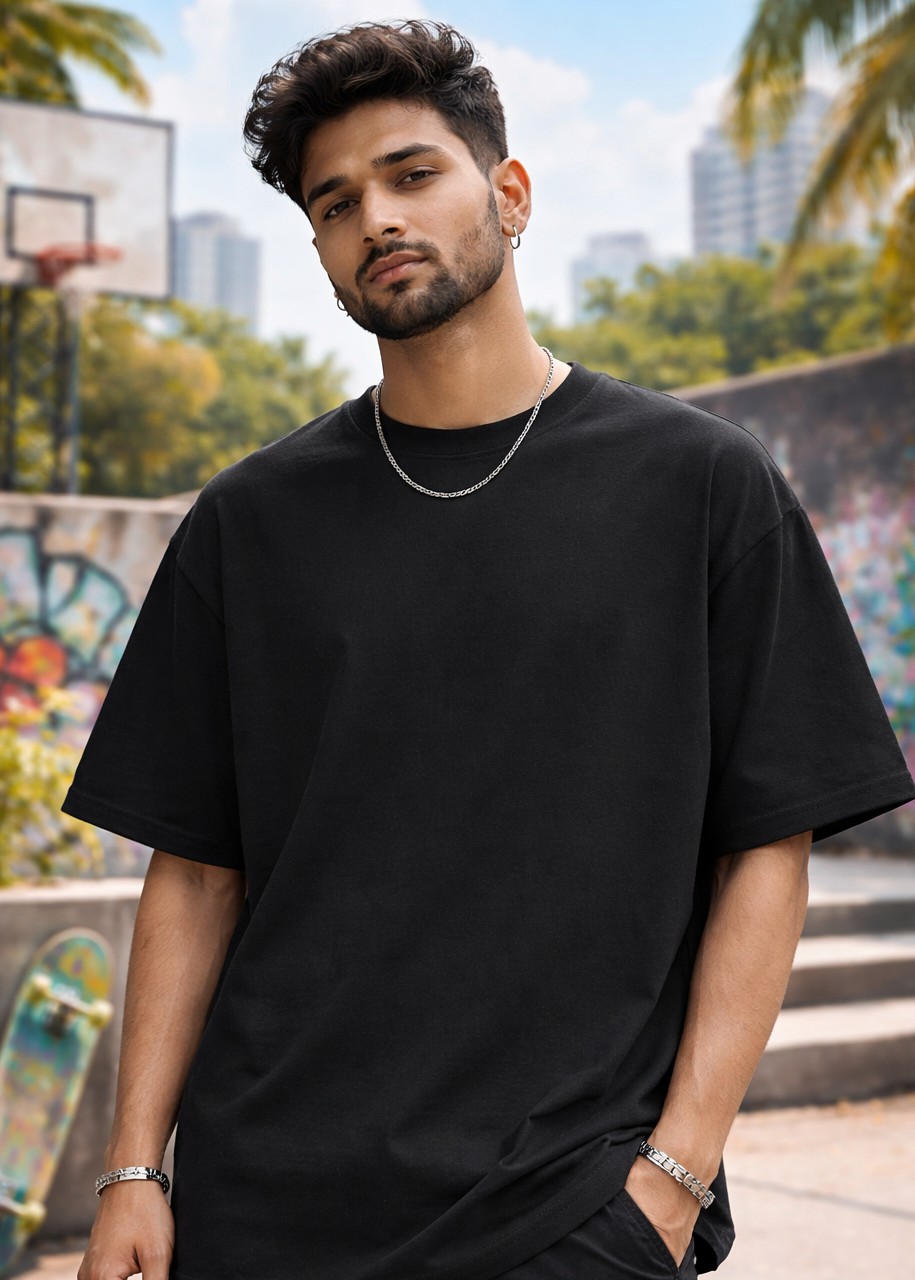 Man wearing a black oversized t-shirt in an urban setting with skateboards and graffiti.